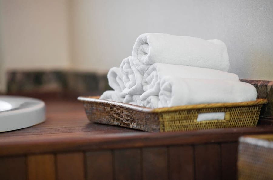 Rolled white cotton bath sheets in a woven basket