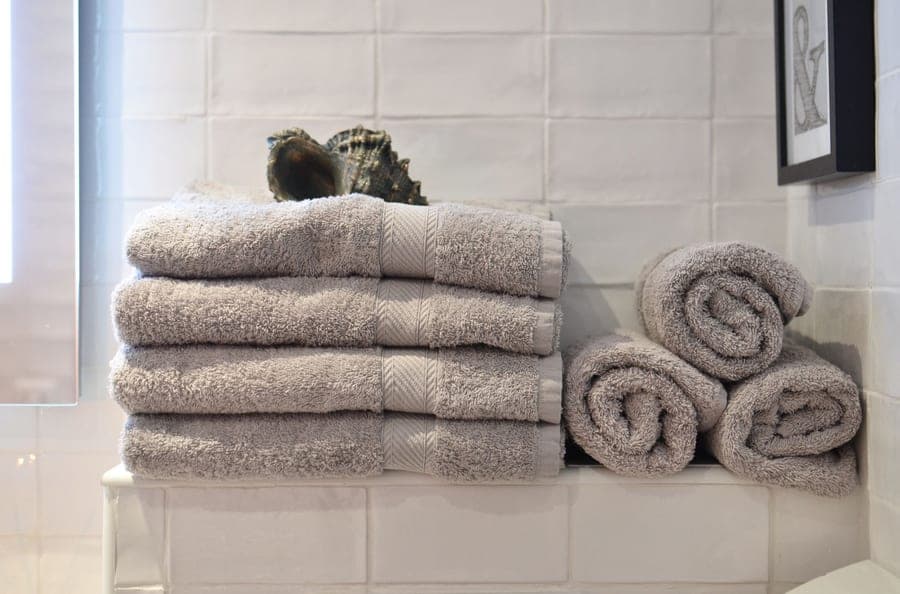 Thick folded and rolled gray bath sheets on a bathroom shelf