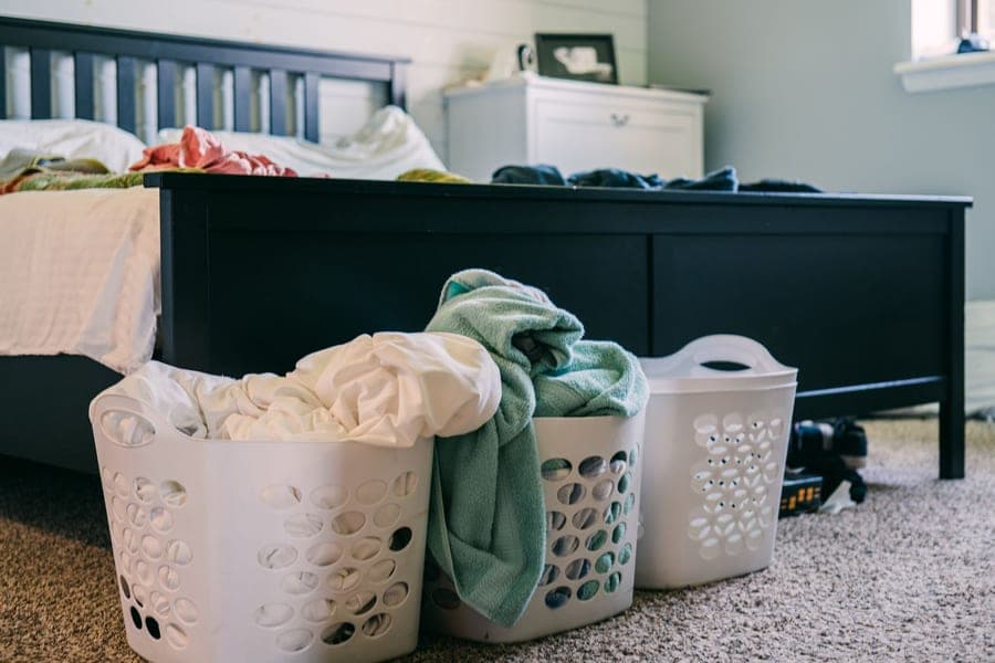 Laundry booster powder beside a laundry basket of towels