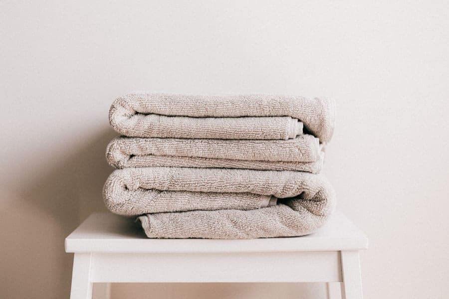 Oversized white resort bath sheet folded on a bench