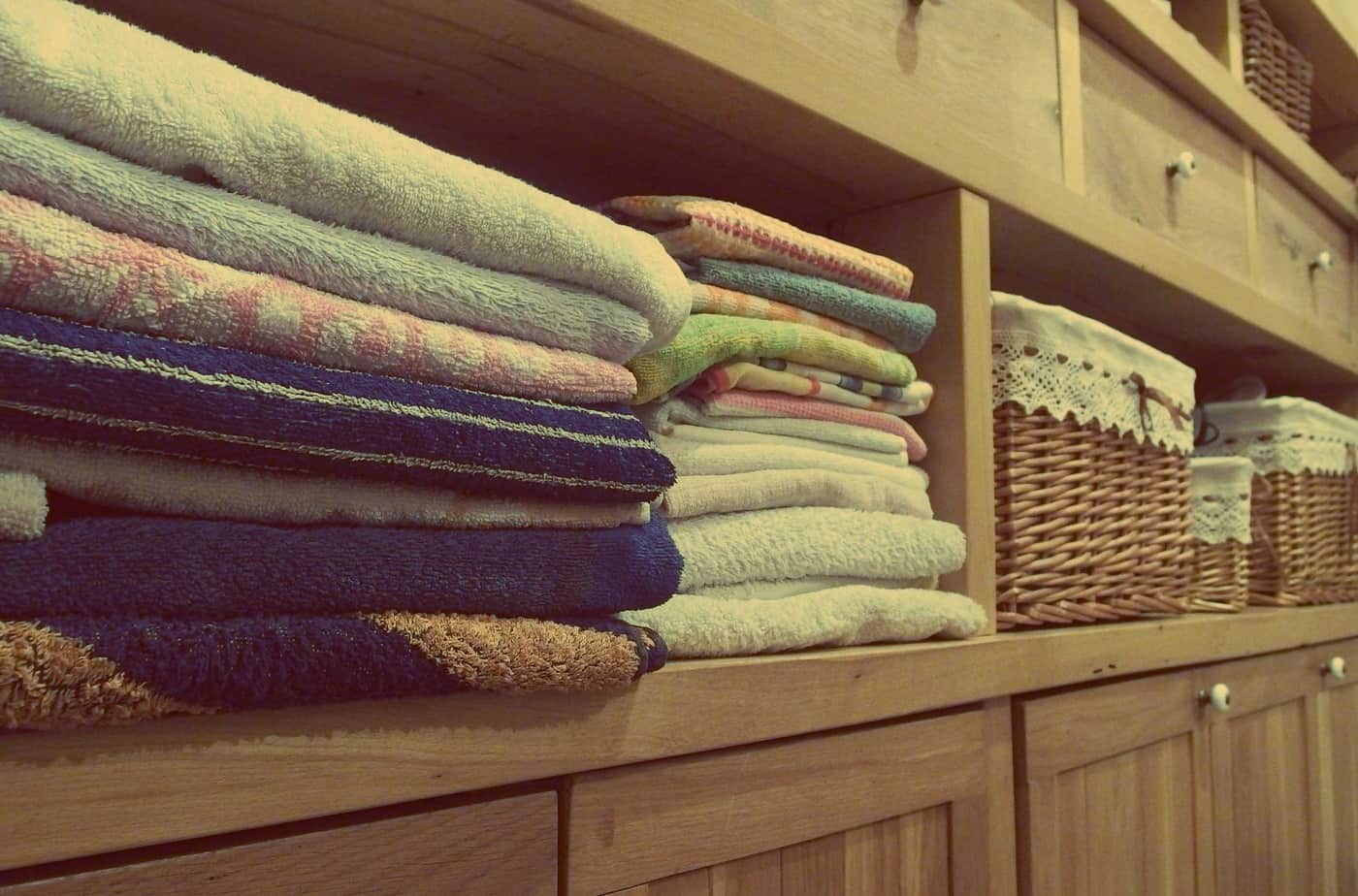 Folded cotton bath towels in cream and gray on a bathroom shelf