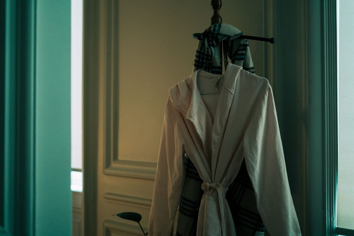 A cotton bathrobe hanging on a wooden hanger in a bathroom
