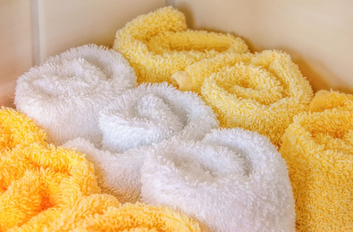 Crisp white hotel towels rolled and stacked on a shelf
